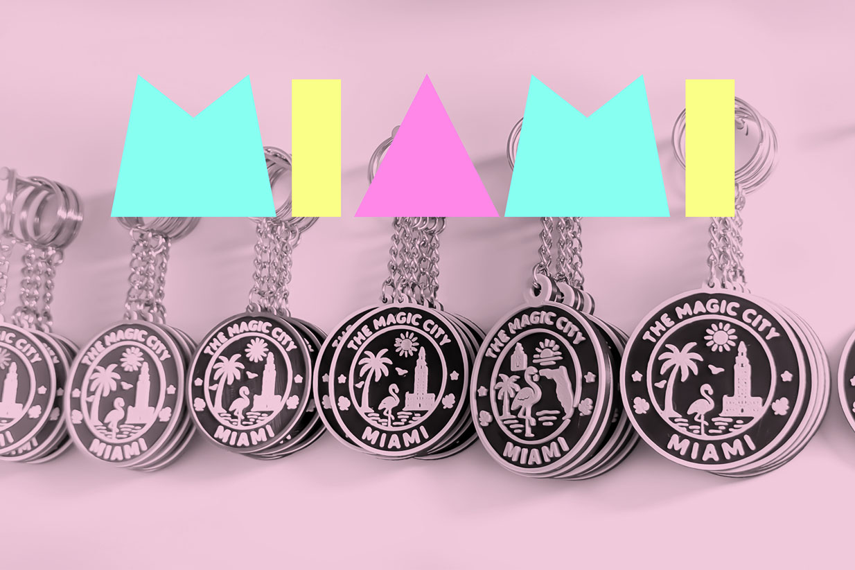 Colorful 3D-printed keychains featuring 'THE MAGIC CITY MIAMI' design, displayed alongside bold geometric shapes in a playful arrangement.